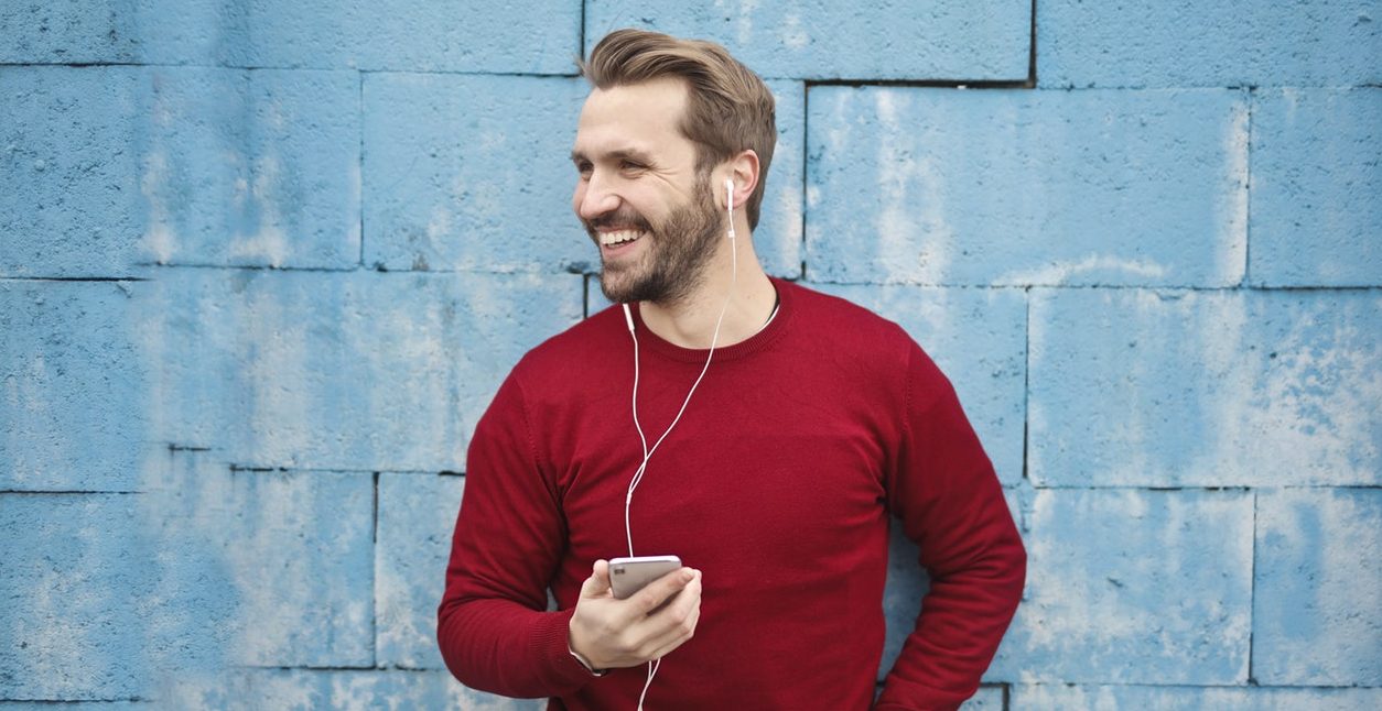 Man with red sweater on phone call with headset and iPhone