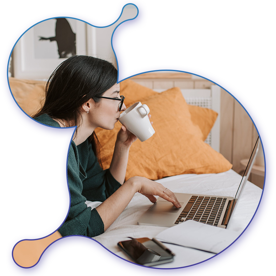 girl learning on computer while laying on the bed and drinking coffee