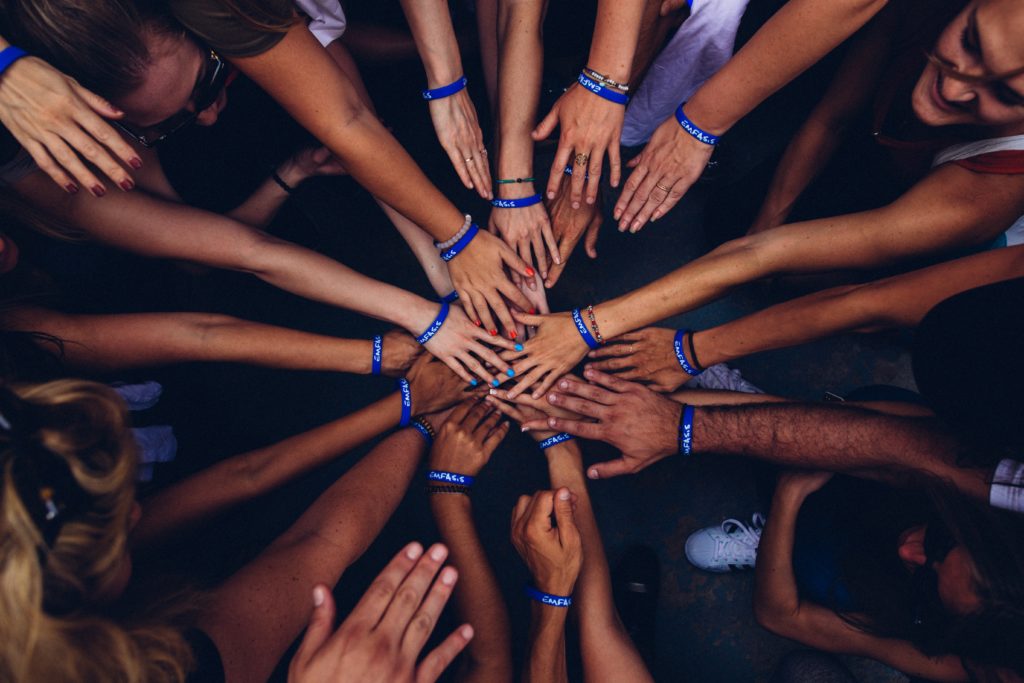 Volunteers gathering in a circle with hands in the middle, technology can be volunteers for charities